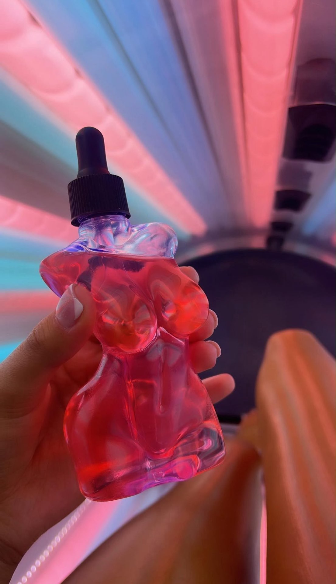 Tropical Tanner body-shaped glow drops under neon light